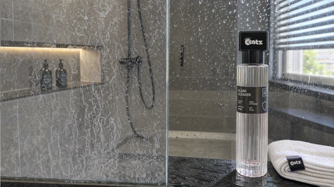 A shower screen split down the middle: the left half clouded with hard water limescale, the right half clear with water beading off it.