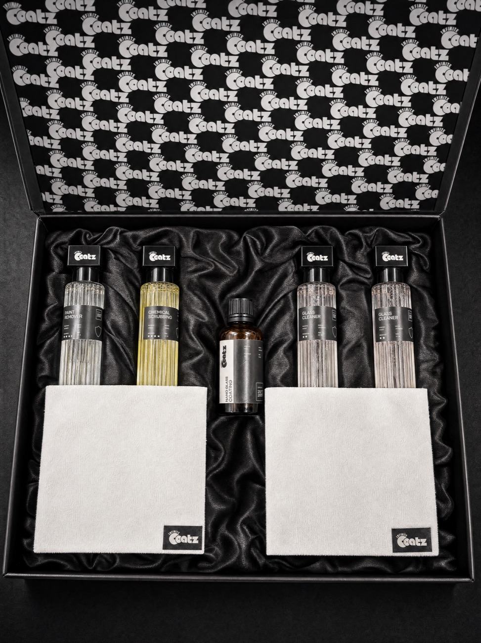 The Infinite Coatz box open, showing the five bottles and two microfiber cloths held in black satin.